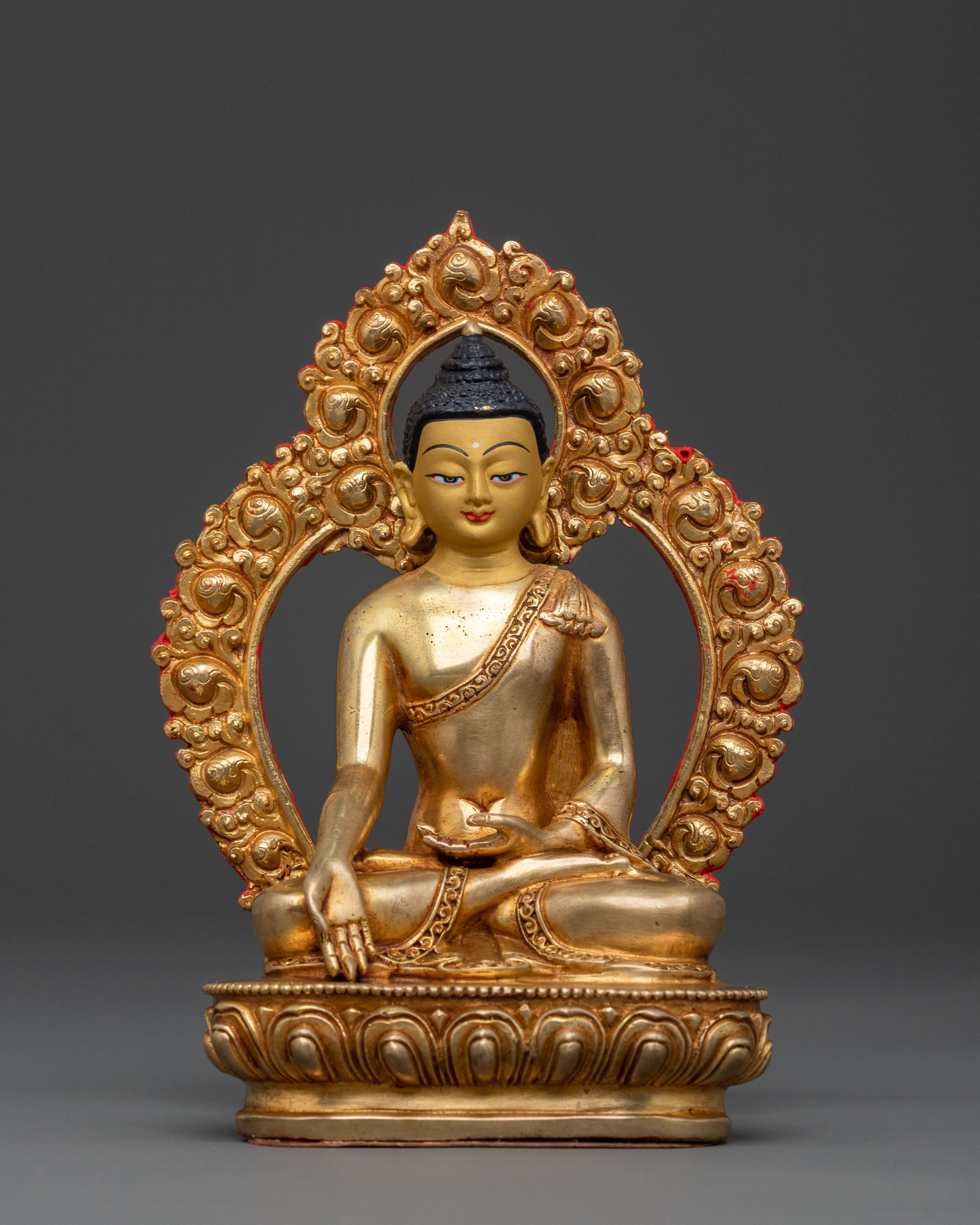 Gold-colored Buddha statue with intricate details on a dark background